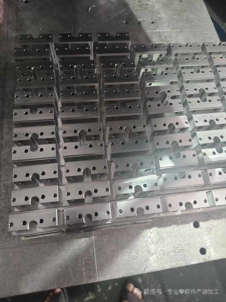 Rows of machined rectangular metal blocks with repeated holes and open slots