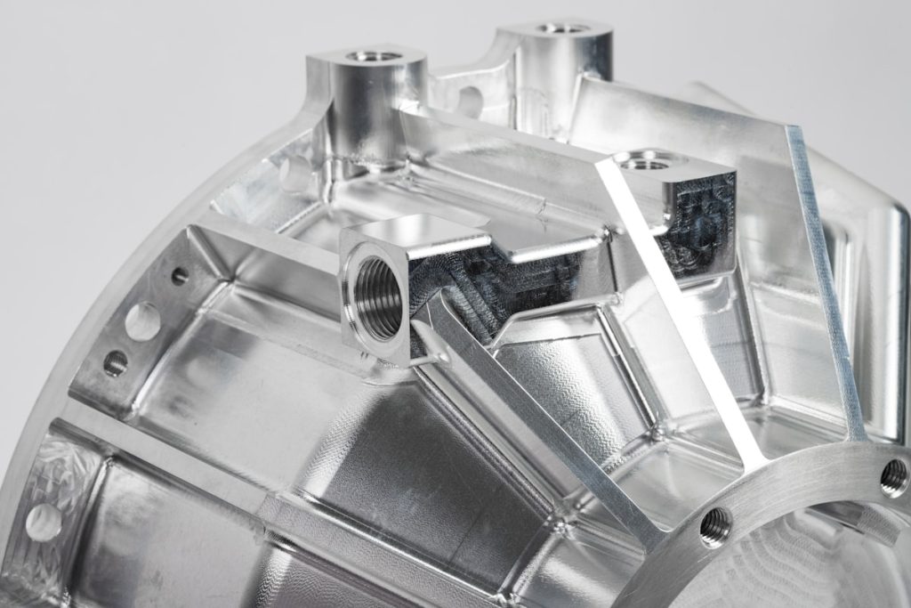Close-up of a machined metal housing with ribs, threaded bosses and several machined faces