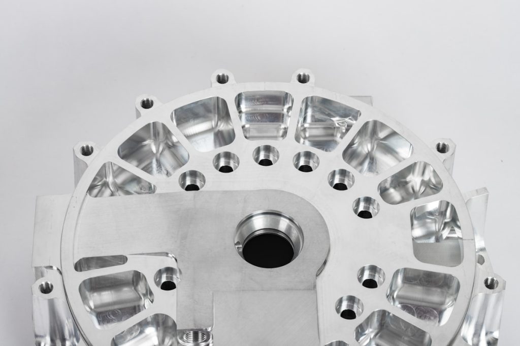 Round pocketed metal plate with a central bore, repeated mounting holes and milled recesses