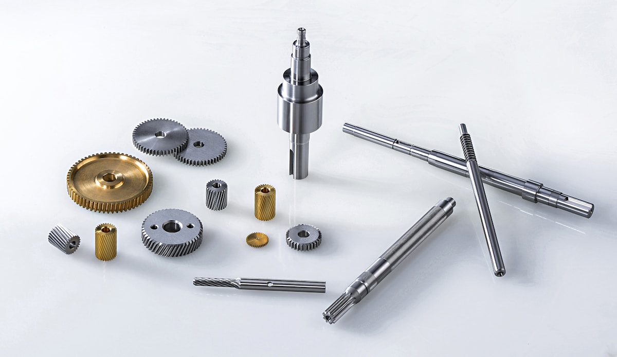 An assortment of machined shafts and gears on a light background